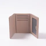 Billetera de cuero sintético beige, diseño compacto de tres pliegues con solapa frontal decorada con ribete metálico dorado y costuras pespunteadas.