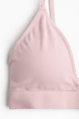 Soutien de diseño seamless, confeccionado en tejido suave de color rosado. Presenta copas forradas con relleno extraíble, breteles ajustables y una banda elástica inferior para mayor sujeción. Su diseño carece de aros y cierres, priorizando la comodidad.