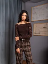 Blusa de encaje negro, manga larga, con escote bote y diseño ajustado al cuerpo.