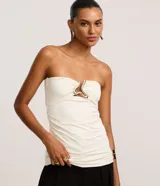 Blusa de microfibra color marfil, de corte palabra de honor, con escote corazón, detalle de cutout central con aplicación metálica dorada y fruncidos laterales.