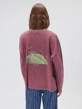 Remera oversize de manga larga color naranja con efecto gastado, cuello redondo y gráfico estampado en la espalda.