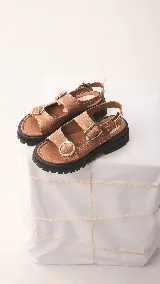 Sandalias de mujer con plataforma gruesa y dentada de color negro. La capellada presenta un estampado de piel de serpiente en tonos beige y marrón, con dos tiras ajustables con hebillas de cuero marrón.