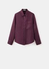 Camisa de lino color bordó con cuello camisero, manga larga con puños abotonados, bolsillo aplicado en el pecho y cierre frontal de botones.