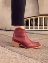 Bota texana de caña baja confeccionada en cuero vacuno con acabado estilo vintage, forrada en cuero. Presenta costuras decorativas en el empeine y taco cuadrado de madera.