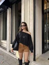 Buzo de cuello bote con diseño de hombro descubierto, confeccionado en tela angorina elastizada, con corte amplio en la parte superior y ajuste en la cintura.