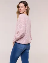 Blusa blanca de organza con textura devoré floral, silueta semiholgada y forro interno. Tiene escote bote, mangas largas abullonadas con transparencias, puños anchos con botones y ruedo elastizado.