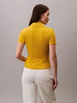 Chomba de punto pointelle texturizado color amarillo, con cuello tipo Johnny abierto, manga corta y ribetes en canalé. Presenta un diseño minimalista con logo bordado sutil en la parte frontal.
