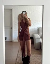 Vestido corto color marrón, con escote halter profundo y detalle de nudo frontal con caída larga. Diseño ajustado al cuerpo.
