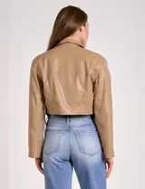 Chaqueta corta de eco cuero color tostado, con cuello alto, cierre frontal con botones a presión y bolsillos de solapa en el pecho. Tiene forro interno a tono.