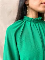 Blusa verde con cuello alto fruncido y mangas largas abullonadas.
