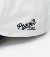 Gorra blanca de sarga con visera azul marino y bordado de Snoopy jugando baseball.