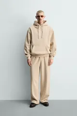 Pantalón jogger de corte relajado y pernera ancha, confeccionado en tejido de algodón con interior perchado. Presenta cintura elástica con cordón interior, bolsillos laterales y un bolsillo trasero de plastrón.
