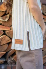 Chaleco tejido de punto acanalado vertical en color negro con hilos de lurex plateados. Presenta cuello redondo, hombros amplios con efecto de hombrera caída y tajos laterales en el ruedo.