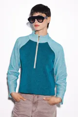 Sweater verde con cierre al cuello, de corte holgado y mangas largas.
