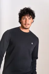 Buzo de cuello redondo en color azul marino, con ajuste elástico en puños y cintura. Presenta un pequeño logo bordado de un pingüino en el lado izquierdo del pecho.