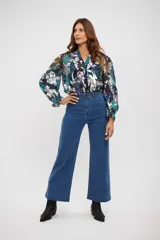 Camisa de manga larga con estampado floral en tonos azul, turquesa y blanco. Presenta cuello en V, cierre frontal con botones y puños elásticos con volados.