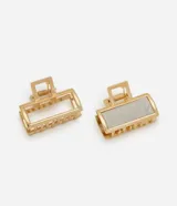 Kit de dos pinzas rectangulares para el cabello con acabado metálico dorado, una con diseño calado y otra con aplique texturizado brillante.