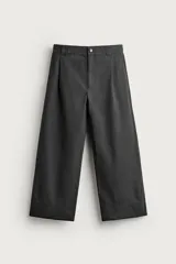 Pantalón wide fit color gris oscuro, de corte ancho y recto, con pliegues frontales en la cintura, bolsillos laterales y efecto lavado. Cuenta con cierre frontal de cremallera y botón.