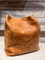 Bolso tipo shopper de cuero con acabado texturizado en tono metalizado claro. Cuenta con doble asa de hombro y etiqueta de cuero con logo grabado en la parte inferior frontal.