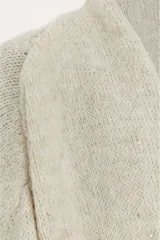 Saco abierto de punto en color beige, con diseño de manga larga y puños acanalados. Presenta un tejido con sutiles destellos brillantes integrados.