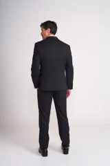 Traje de vestir negro de tres piezas, compuesto por saco, chaleco y pantalón. El saco es de corte clásico con solapa de muesca y dos botones. El chaleco es de cinco botones y el pantalón es de corte recto.
