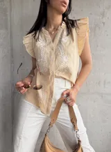Blusa color beige con bordado floral blanco en el frente, cuello en V y mangas cortas con volados.