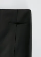 Pantalón negro acampanado de lana, con dos bolsillos de ribete en la parte delantera.
