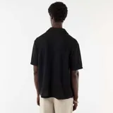 Camisa de punto calado negro, de manga corta, con cuello solapa y cierre frontal de botones.