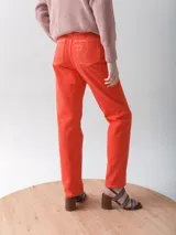Pantalón de jean recto color naranja con costuras blancas.