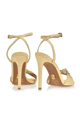 Sandalia de tacón alto color amarillo con pulsera al tobillo y detalle de moño con strass en la capellada.