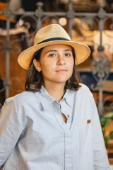 Sombrero de estilo fedora confeccionado en material tejido color tostado, con una franja decorativa negra alrededor de la copa.