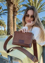 Bandolera Chabas de cuero marrón con textura tipo piel de reptil. Tiene correa larga regulable y logo de la marca en el frente.