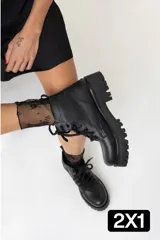 Borcegos de cuero negro con cordones, suela track y caña baja.