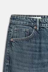 Jeans de tiro medio con corte relajado y diseño de cinco bolsillos. Presenta trabillas en la cintura, cierre frontal con cremallera y botón metálico, con un acabado de lavado desgastado.
