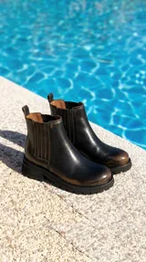 Bota tipo chelsea de cuero con acabado desgastado, paneles laterales elásticos y suela track robusta.