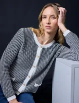 Cardigan de tweed color negro con estampado pata de gallo, de la marca Ninety. Tiene escote redondo, cierre frontal con botones dorados, bolsillos simulados y ribete blanco en cuello, puños y ruedo.