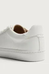 Zapatilla de estilo minimalista con cordones, confeccionada en material sintético de acabado mate. Presenta una horma redonda, forro interior en tono contrastante y suela de goma con textura ligera.