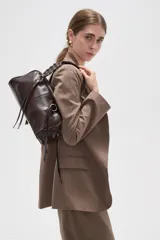 Bolso de cuero sintético color marrón, con diseño de hombro, tiras colgantes y detalles de argollas metálicas.