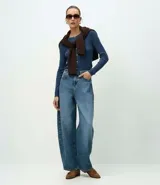 Cardigan de punto canelado con cuello redondo, manga larga y cierre frontal abotonado. Presenta un diseño ajustado al cuerpo y textura acanalada vertical.