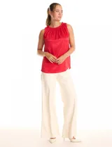 Blusa sin mangas color rojo, confeccionada en satén labrado con un patrón sutil de corazones. Presenta cuello alto con detalle de punto smock fruncido.