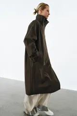 Trench oversize de Zara Woman Collection, confeccionado en mezcla de algodón con estampado de cuadros pequeños. Presenta cuello alto, cierre frontal con botones, mangas largas con trabillas ajustables y bolsillos laterales.