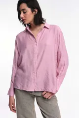 Camisa color marrón de corte oversized, con abotonadura frontal y en las mangas. Presenta un corte vertical en la espalda con lazos decorativos.