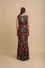 Vestido largo negro íntegramente bordado con lentejuelas en tonos fucsia y verde, con diseño floral, escote redondo y transparencias en la parte superior.