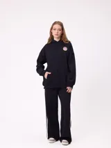 Pantalon de jogging de corte ancho, color negro con rayas laterales blancas. Posee cintura elastizada con cordón de ajuste y logo bordado en la parte frontal.