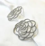 Par de aros plateados con forma de flor calada con incrustaciones de zirconia.