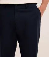 Pantalón de vestir azul marino, de corte relajado, confeccionado en tejido de viscosa y lino. Cuenta con cintura con trabillas, bolsillos laterales y traseros. Se ajusta a la cintura con cinturón de cuero marrón.