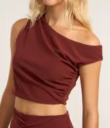 Blusa cropped de crepé color borgoña, con escote asimétrico, manga corta y fruncido lateral.