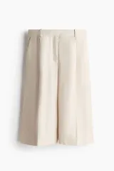 Bermuda de tiro alto en mezcla de lyocell, color beige, con piernas amplias, pinzas, raya planchada al frente y atrás, bolsillos al bies y bolsillos traseros insertados.
