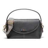 Bandolera de PU color negro con textura de cuero granulado y costuras blancas visibles. Presenta una solapa frontal con cierre metálico dorado y un logo metálico con las letras "XL". Incluye un asa superior corta y una correa larga, regulable y desmontable con estampado de cebra en blanco y negro.