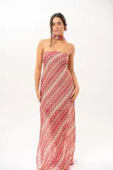 Vestido largo de crochet con escote strapless y lazo integrado para el cuello, con diseño de patrón en zigzag en tonos rojos, blancos y beige, y aberturas laterales en la falda.